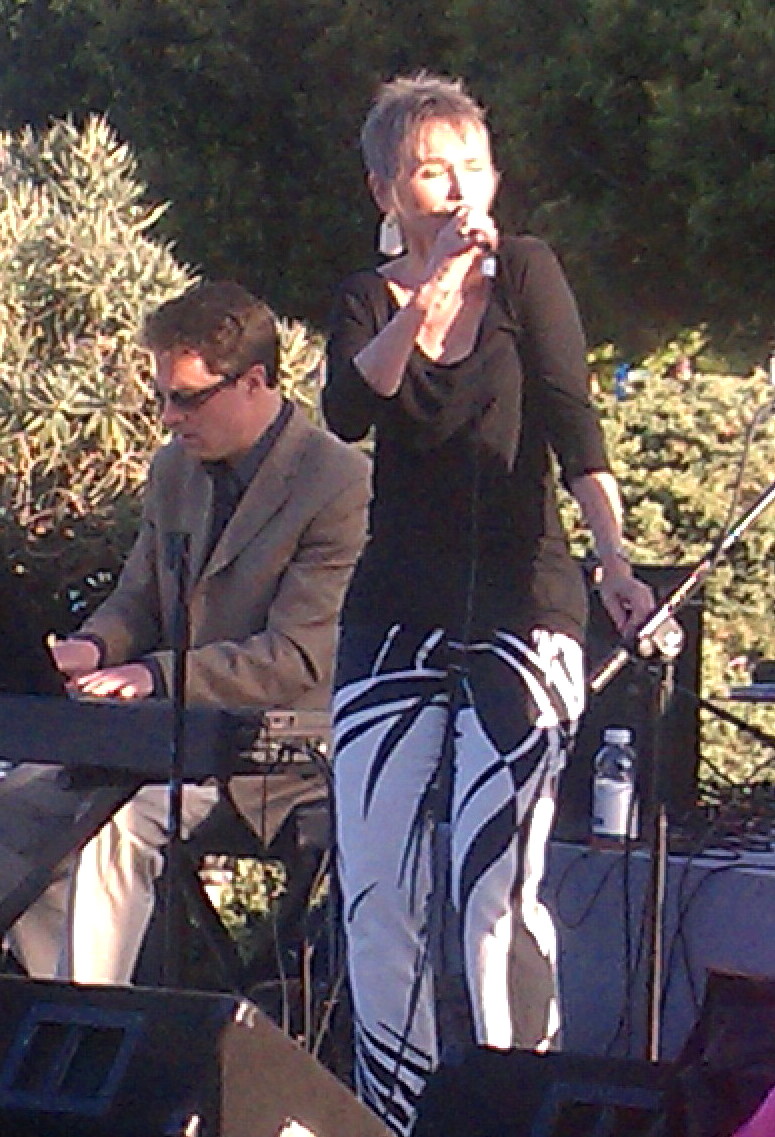 Audrey singing beside the keyboardist at an outdoor evening show