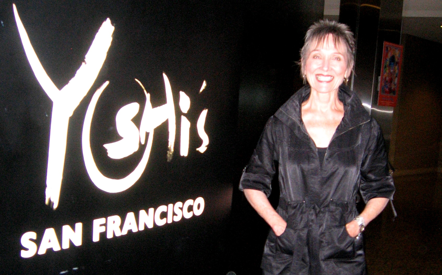 Audrey smiling beside the Yoshi's San Francisco sign