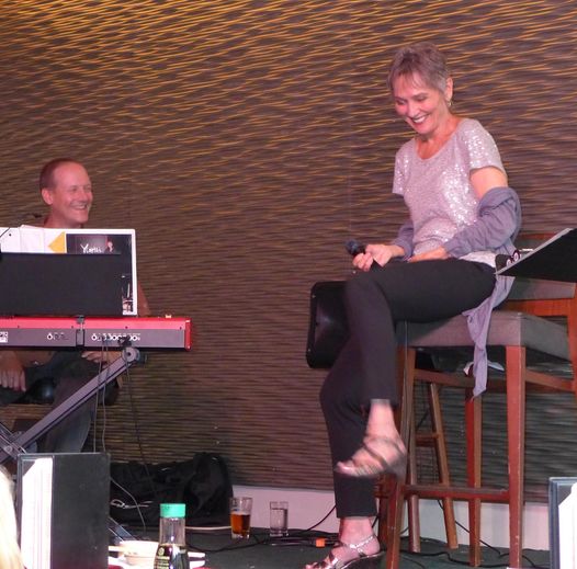 Audrey laughing on a stool beside the keyboardist at Yoshi's in 2013