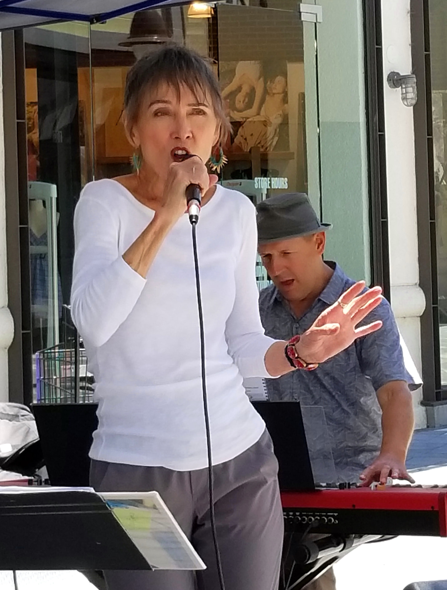 Audrey singing outdoors while the keyboardist plays behind her
