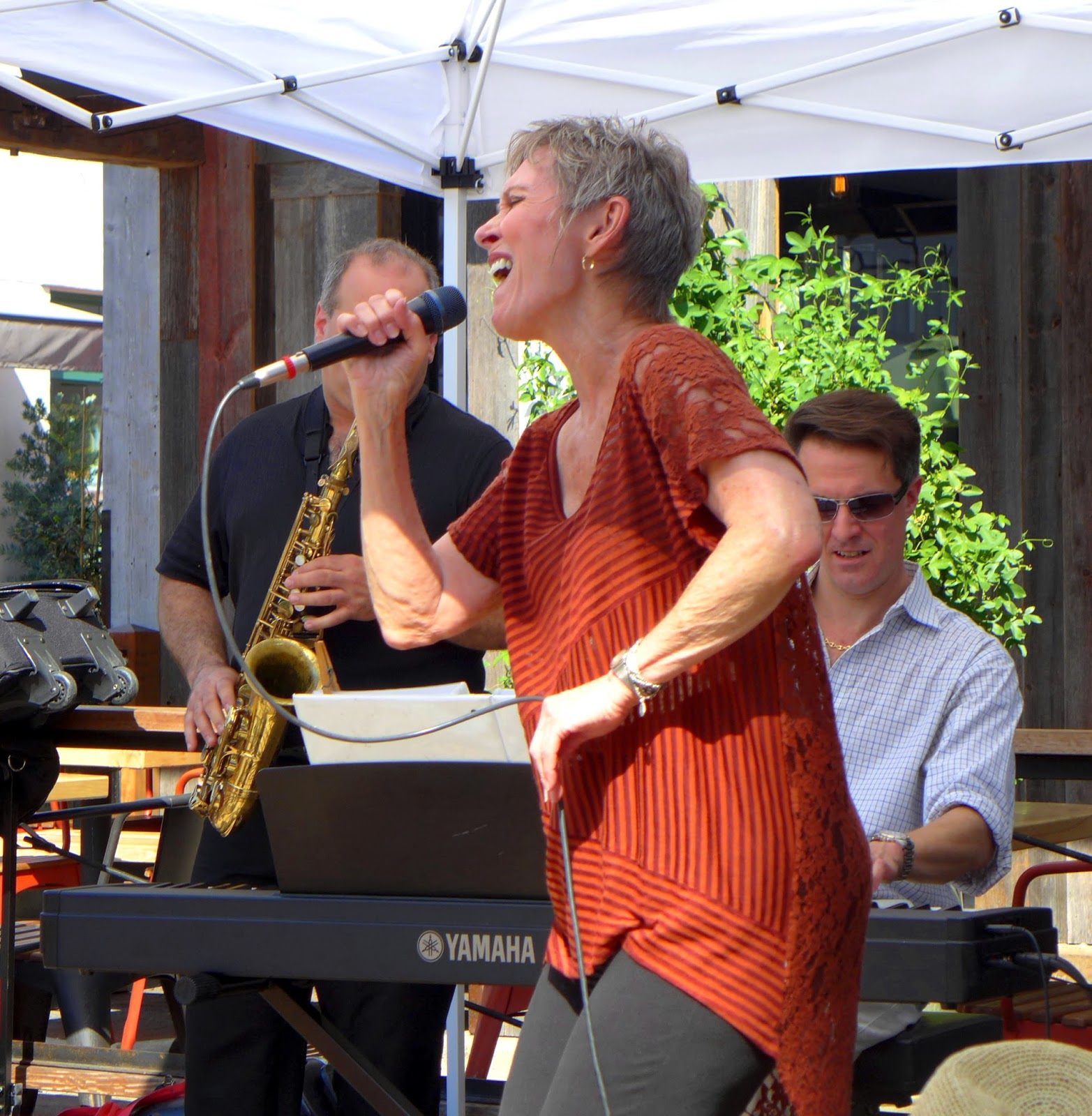 Audrey singing with saxophone and keyboard behind her at an outdoor set