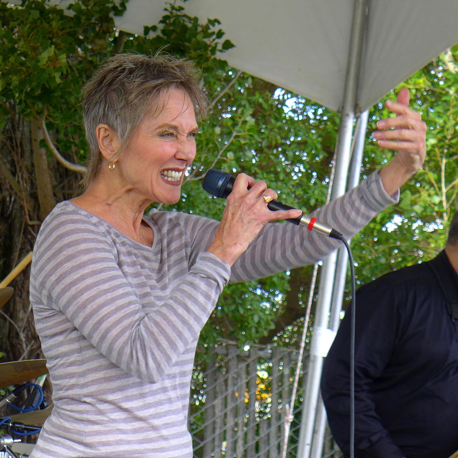 Audrey Moira Shimkas singing with expressive intensity at an outdoor show