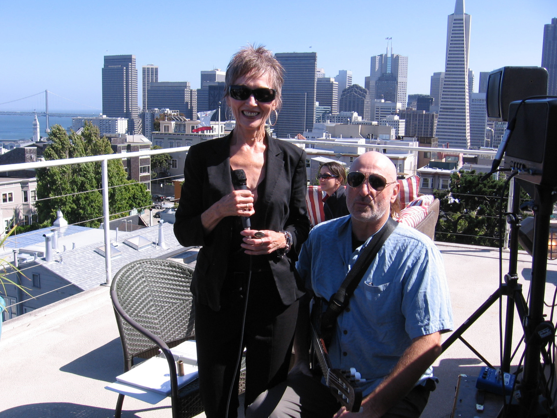 Audrey singing on a rooftop with the San Francisco skyline behind her