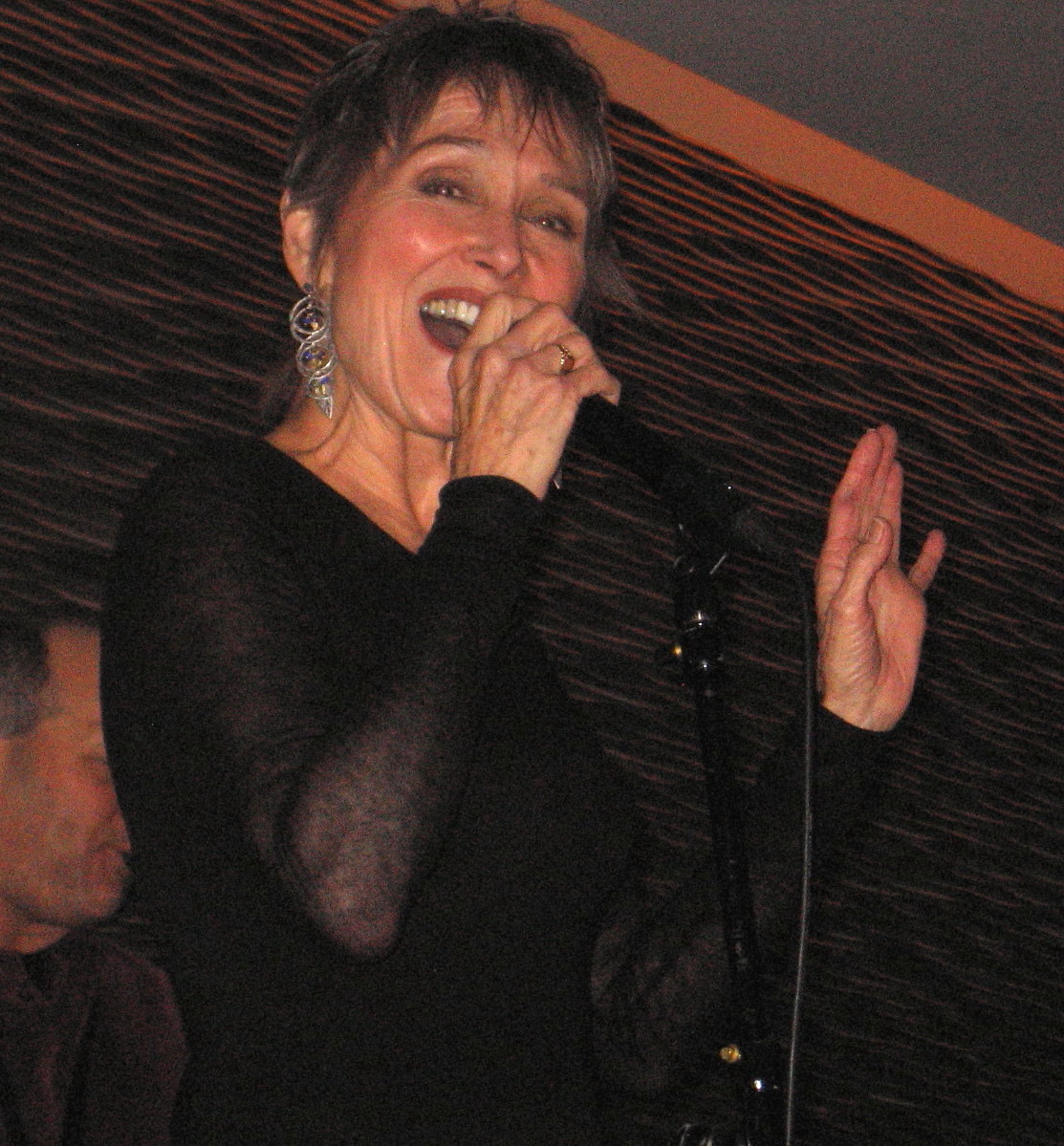 Close-up of Audrey singing into a handheld microphone at a club