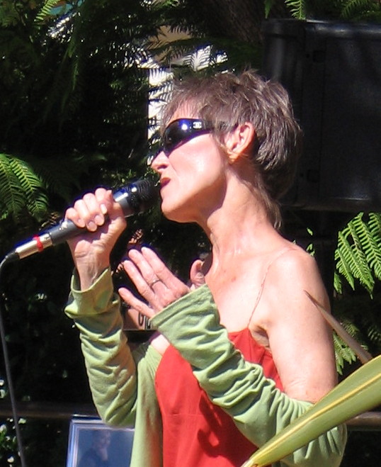 Profile of Audrey singing into a handheld microphone outdoors