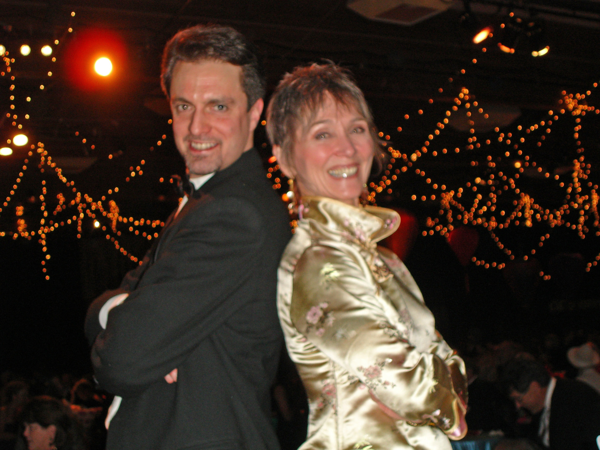 Audrey with a bandmate back to back under string lights at a gala